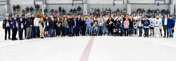 Players from both hockey teams, event organizers, honorees pose for a group photo.
